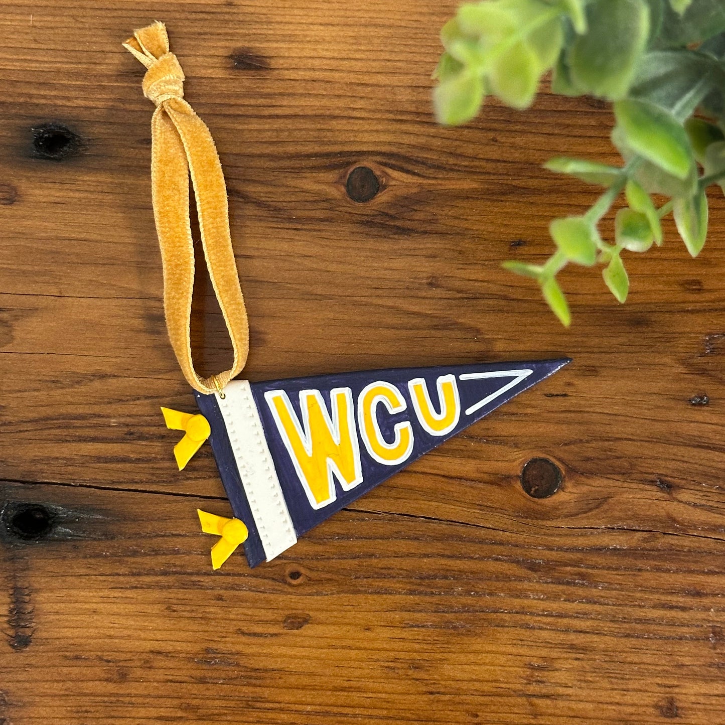 Decorative flag ornament with 'WCU' on a wooden surface