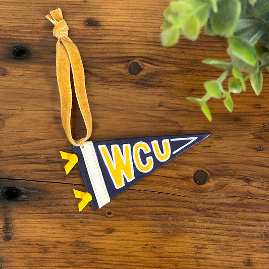 Decorative flag ornament with 'WCU' on a wooden surface